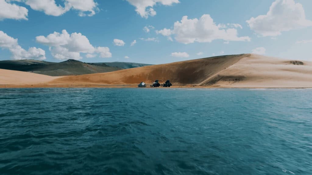 An offroad tour in North Mongolia camped on the side of Khuvsgul lake with two 4x4 cars that have rooftop tents