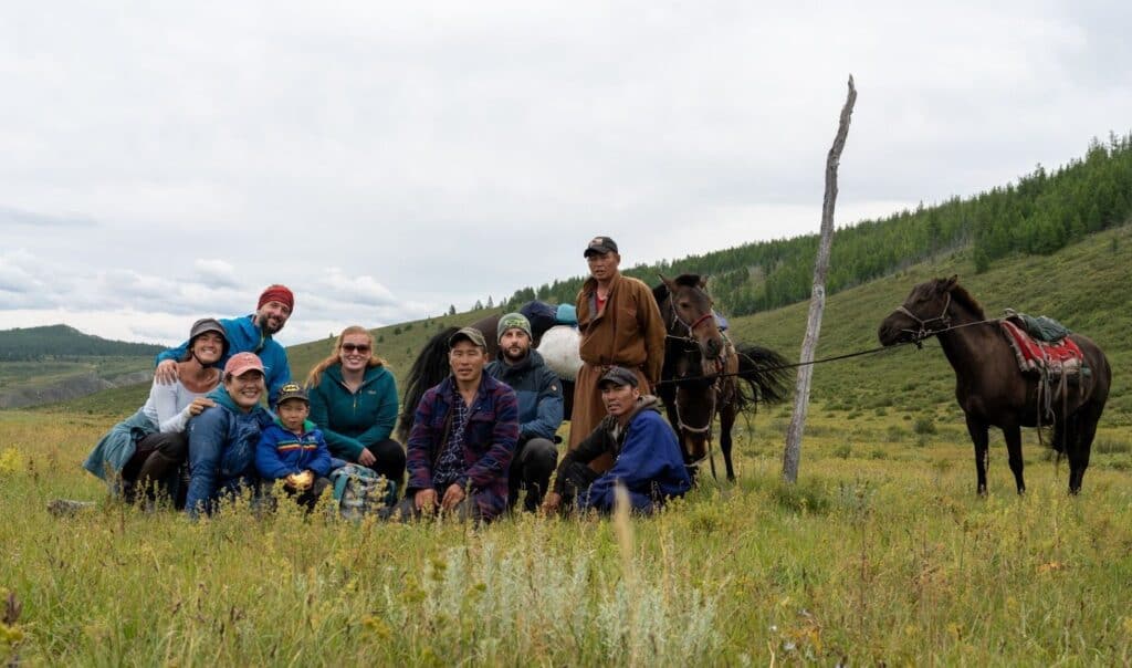 A group of people with horses in the grasslands of Mongolia