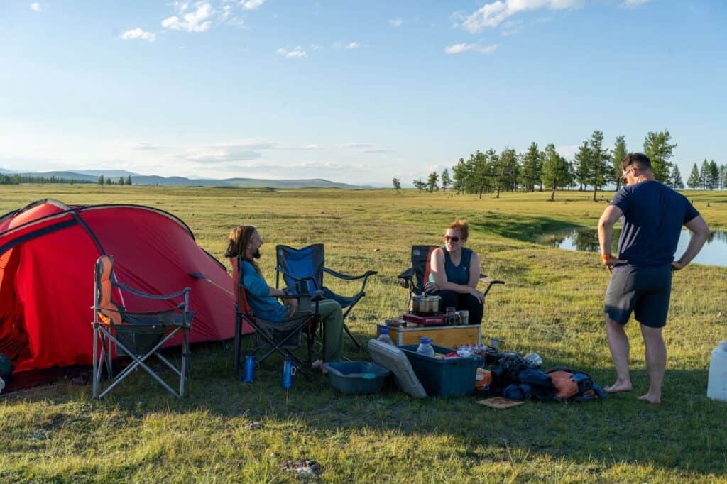 A small group of friends camping in a wide grassland.