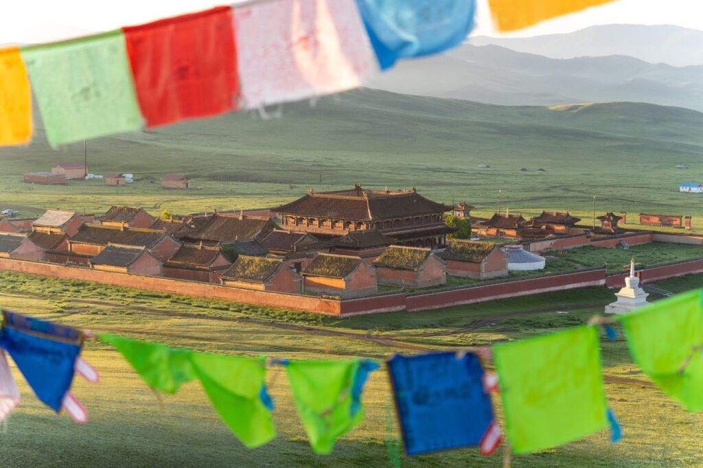 A mongolian monastery viewed through a colorful set of tibetan flags.