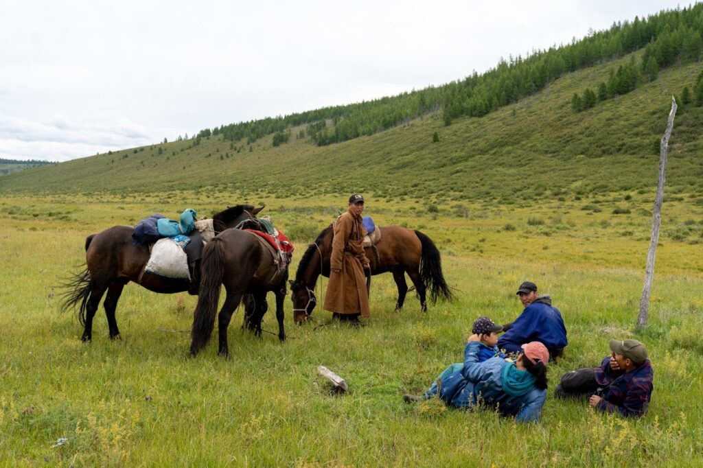 Group of nomad's laying in the grass with their horses