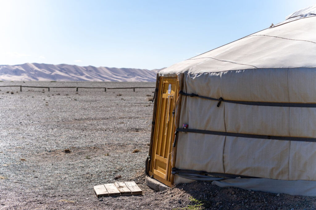 A ger camp in the middle of the desert with the sand dunes in the background.
