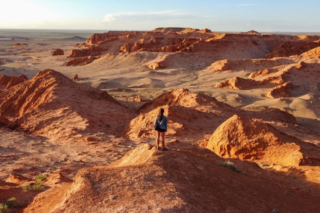 Woman standing on a cliffside looking out on an orange cliff