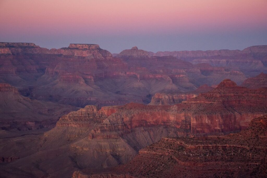 Pink-hued photo of the grand canyon at sunrise.