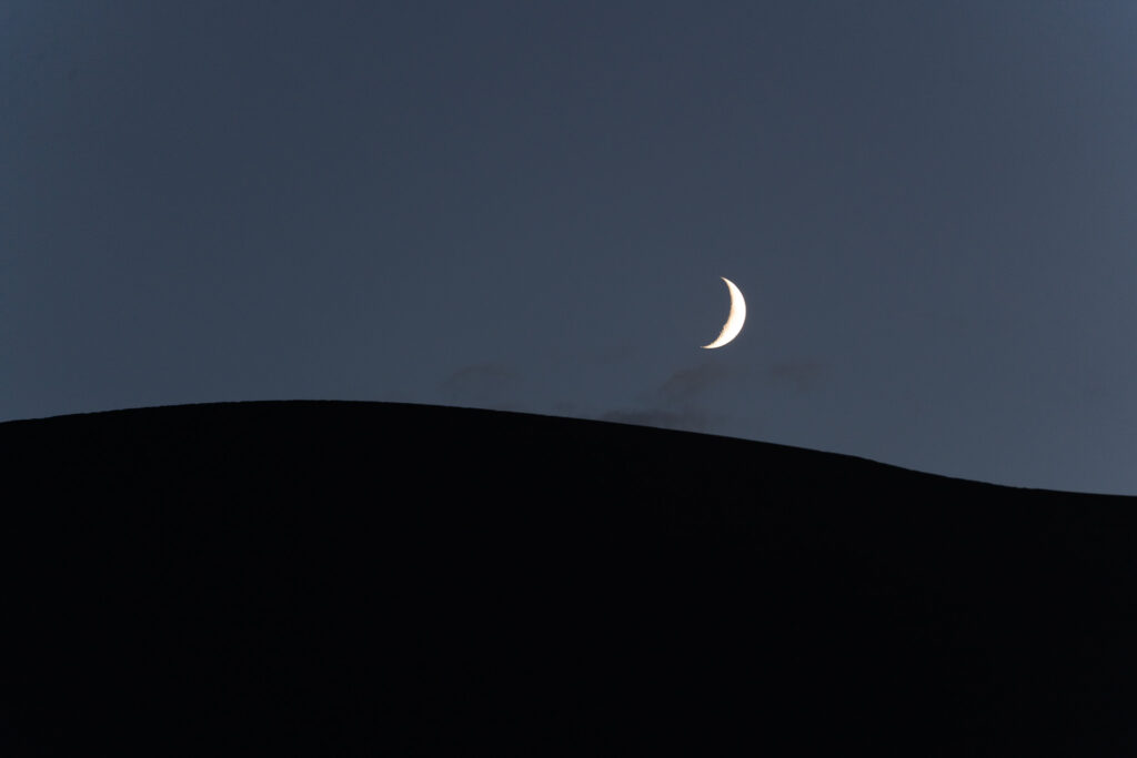 Moon atop a sand dune