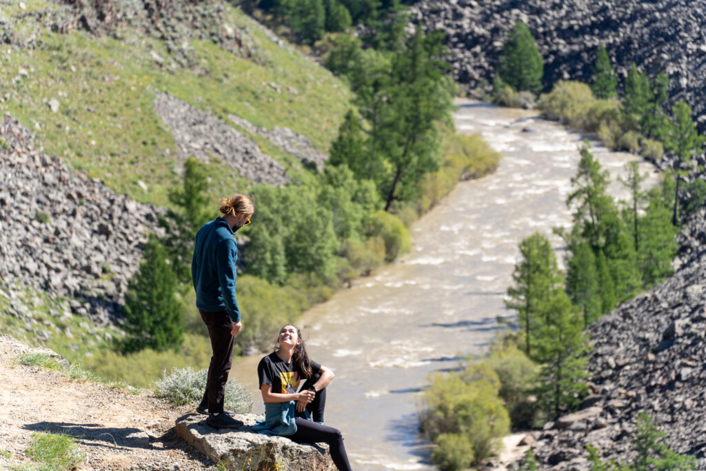 Couple sitting on a cliff edge above a river